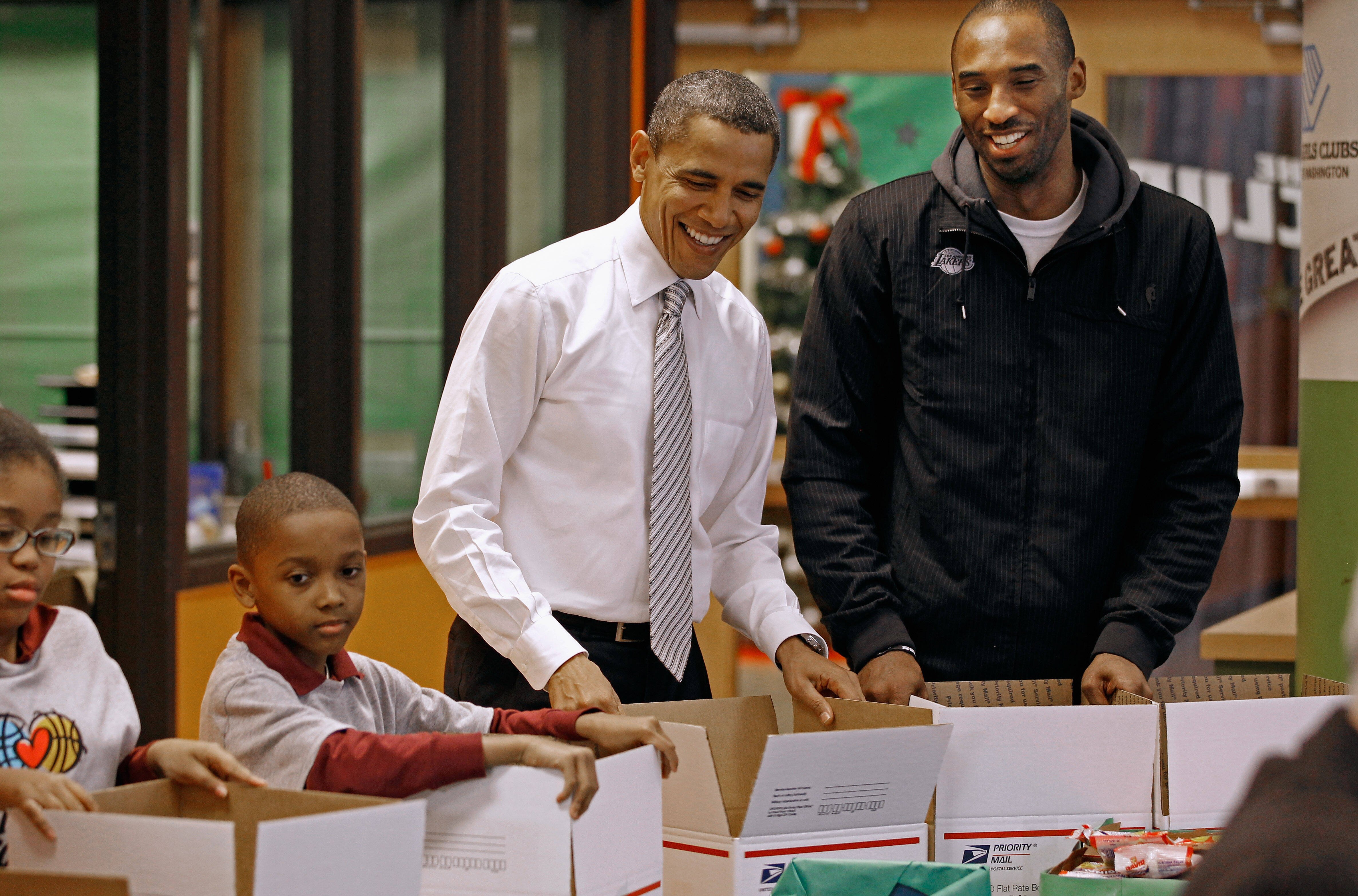 Foto von US-Präsident Barack Obama (Mitte) und Kobe Bryant, Guard der Los Angeles Lakers, wie sie gemeinsam mit freiwilligen Kindern Hilfspakete während einer NBA-Cares-Aktion im Boys and Girls Club packen.