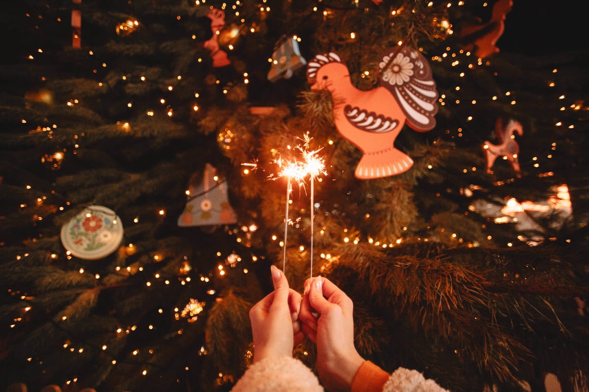 Hands holding sparklers in front of luminous Christmas image