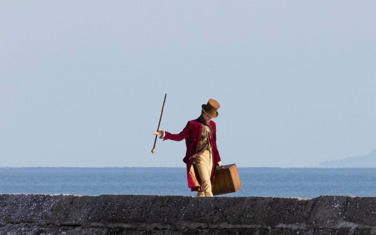 Timothee Chalamet walks along the Cobb in Lyme Regis where filming is taking place of the new Wonka film by Warner Brothers.