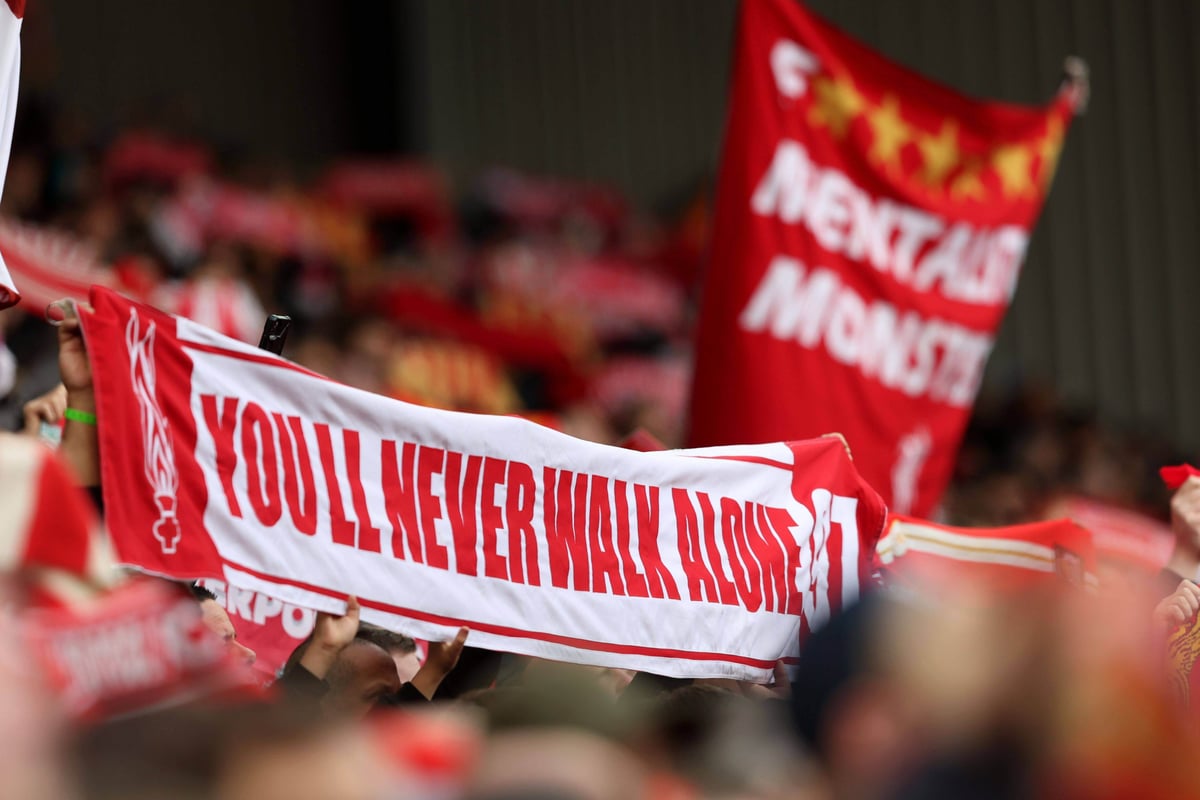   Liverpool fans hold up a flag “You’ll never walk alone”.