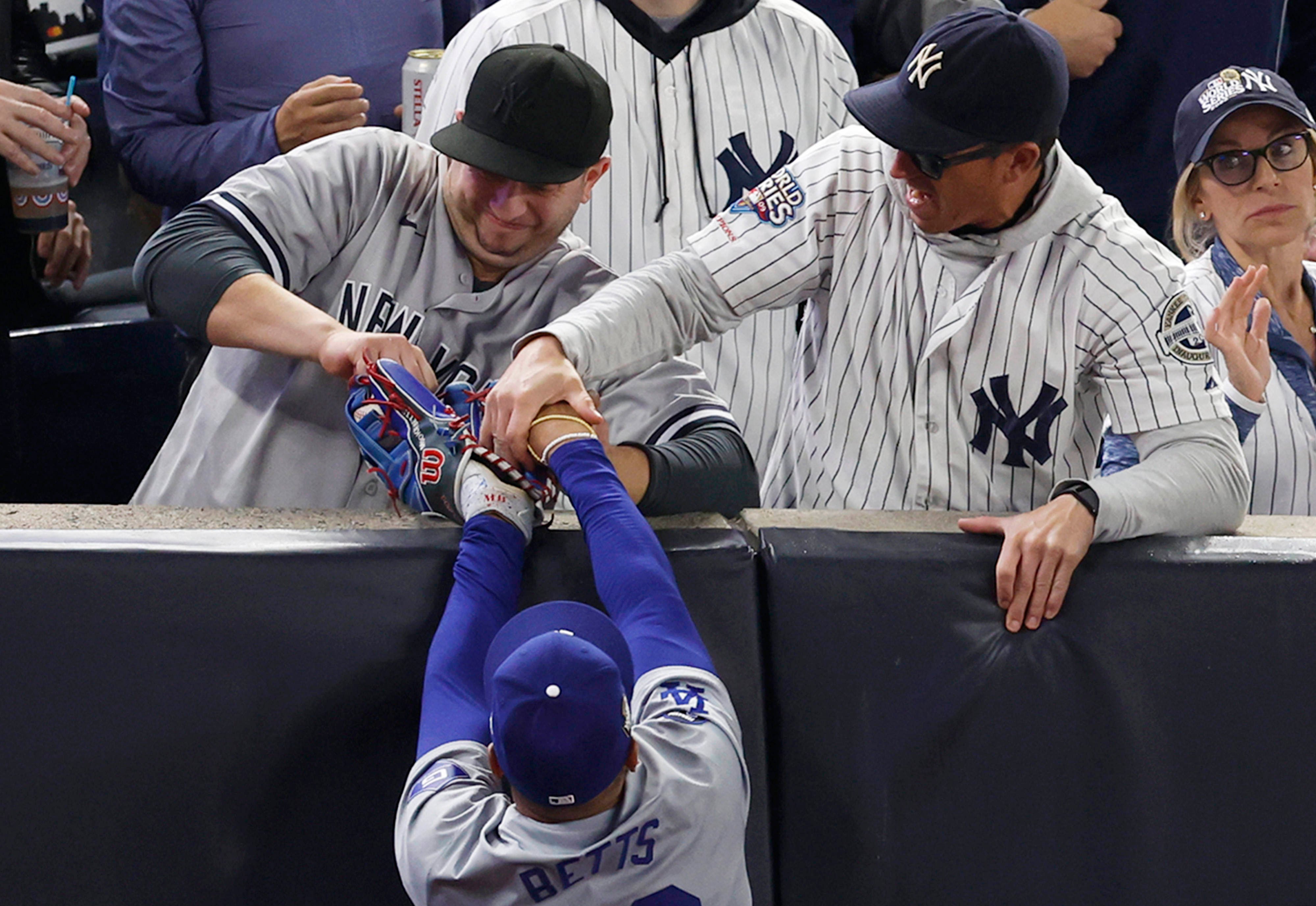 Fans aggressively try to wrestle the ball out of Los Angeles Dodgers right fielder Mookie Betts glove who leaps to attempt to catch a foul ball.