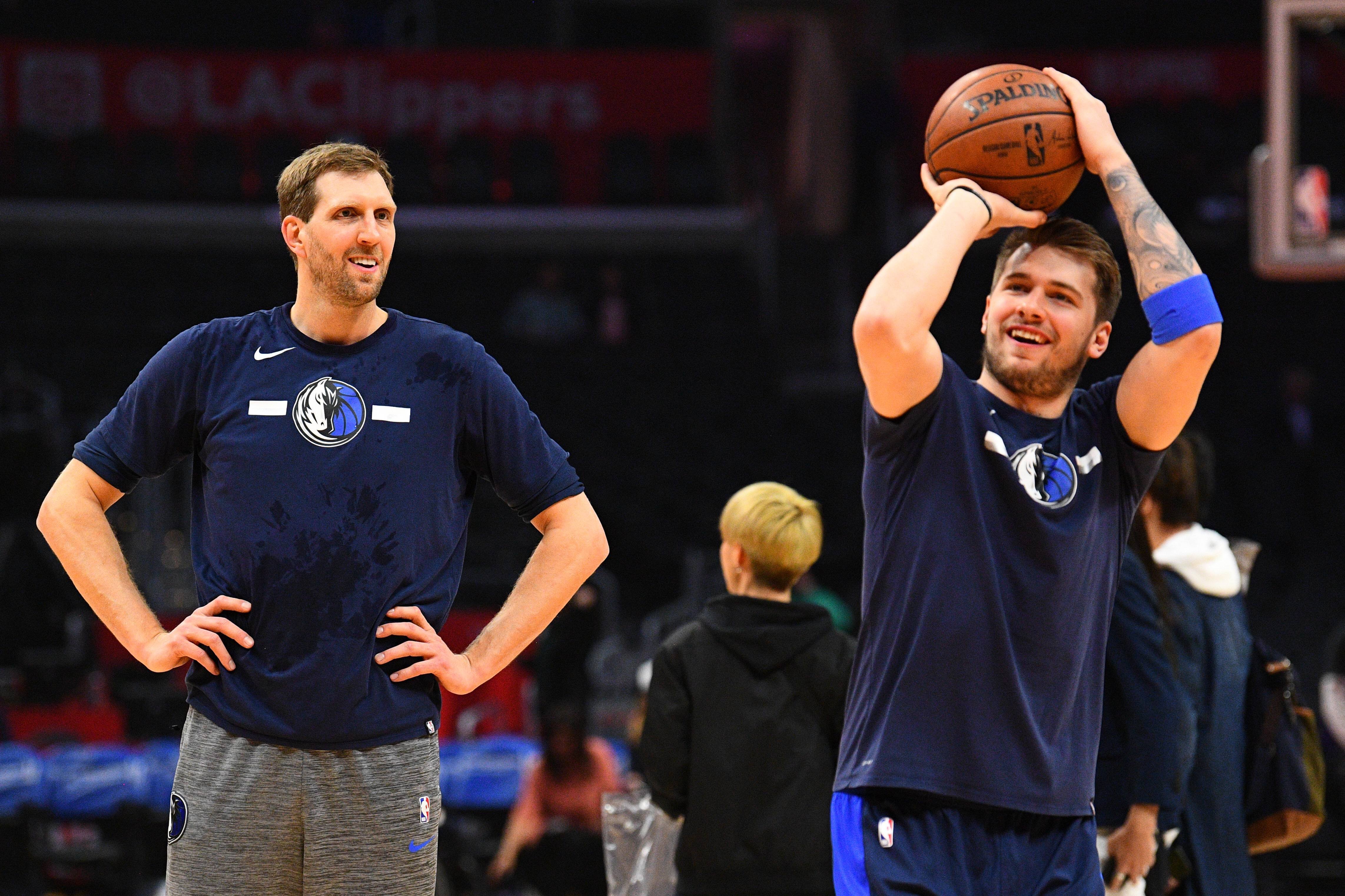 Foto von Dallas Mavericks Forward Dirk Nowitzki (41), wie er Guard Luka Dončić (77) beim Wurf vor einem NBA-Basketballspiel zwischen den Dallas Mavericks und den Los Angeles Clippers zusieht.